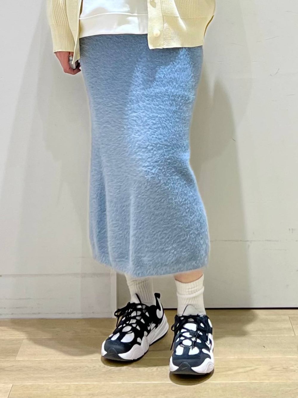 ホワイト系のショルダーバッグ、ブルー系のスカート、ホワイト系のカーディガン/ボレロを着用したレディースの冬コーディネートの5枚目の写真