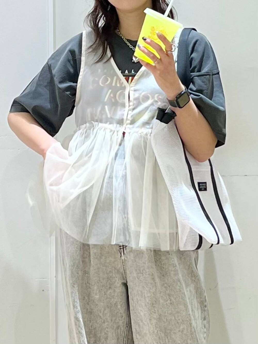 グレー系のデニムパンツ、ベージュ系のベスト、グレー系のTシャツ/カットソーを着用したレディースの春コーディネートの4枚目の写真