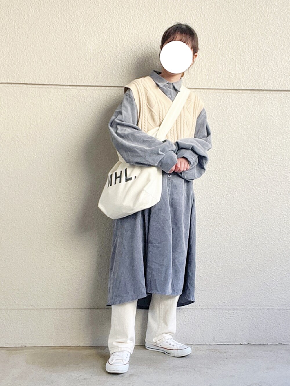 ブルー系のワンピース、ベージュ系のベスト、ホワイト系のデニムパンツを着用したレディースの春コーディネートの2枚目の写真