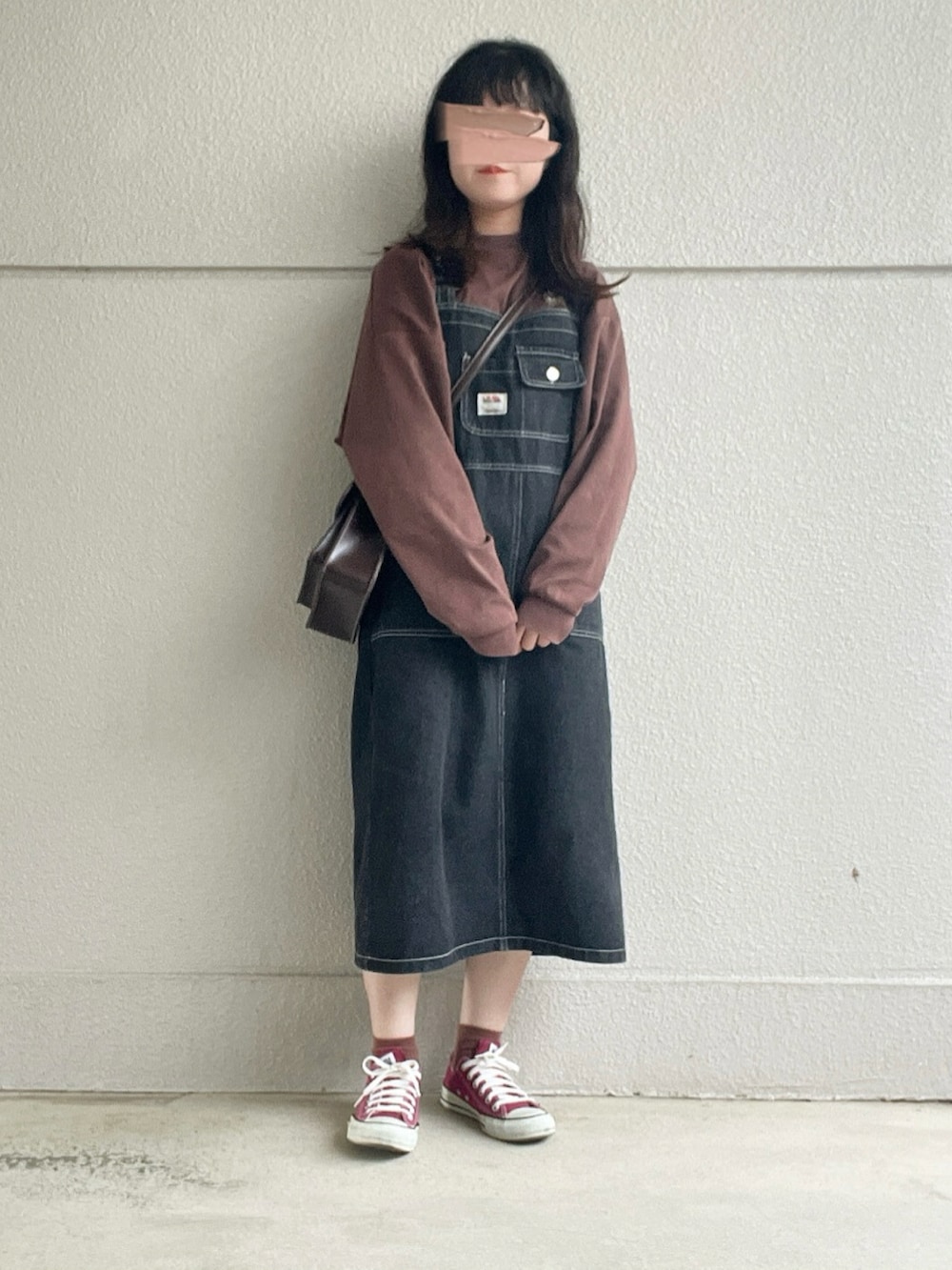 ブラウン系のTシャツ/カットソー、ブラック系のジャンパースカート、ブラウン系のショルダーバッグを着用したレディースの秋コーディネートの2枚目の写真