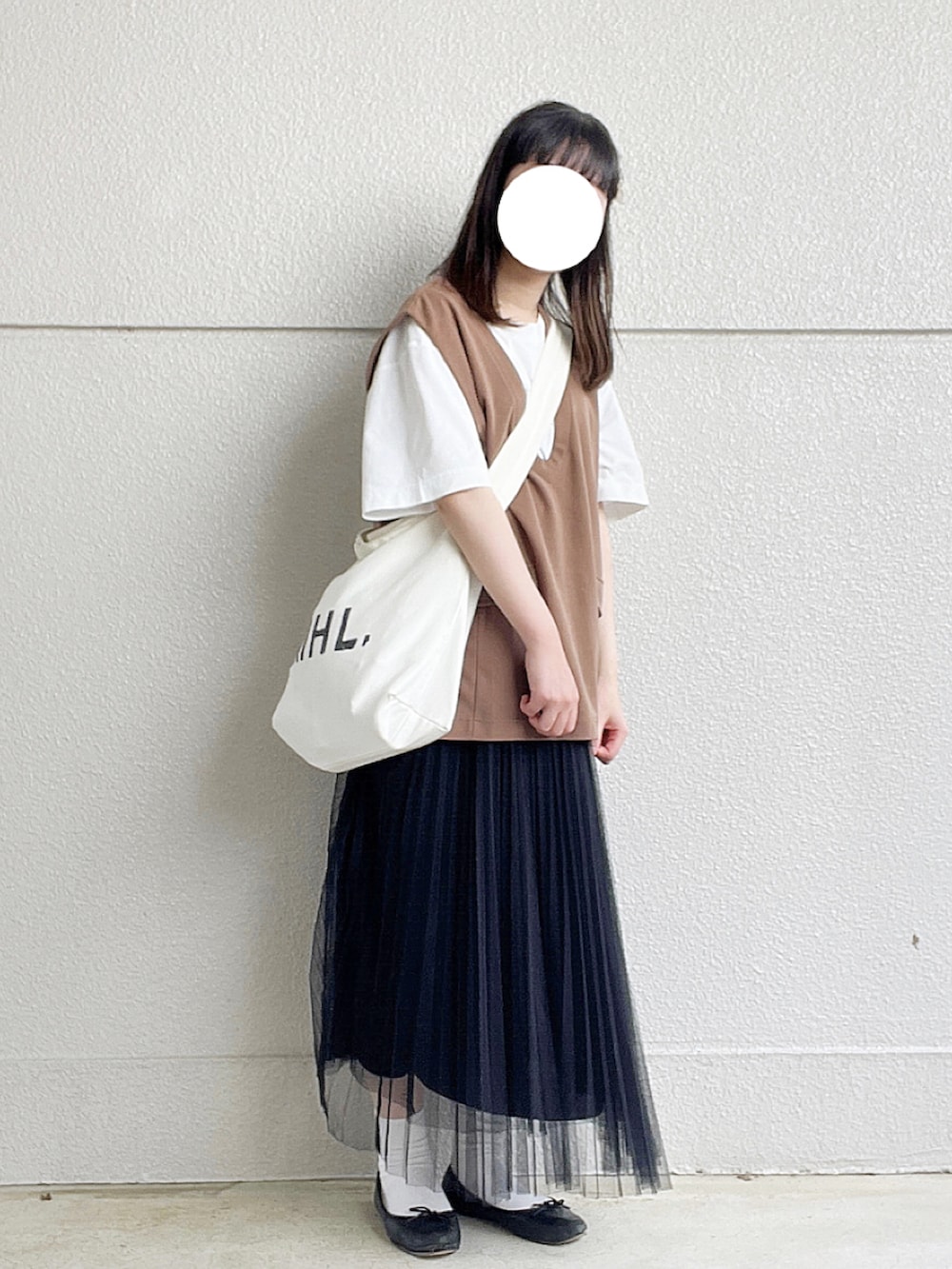 ホワイト系のTシャツ/カットソー、ブラウン系のベスト、ブラック系のスカートを着用したレディースの秋コーディネートの2枚目の写真