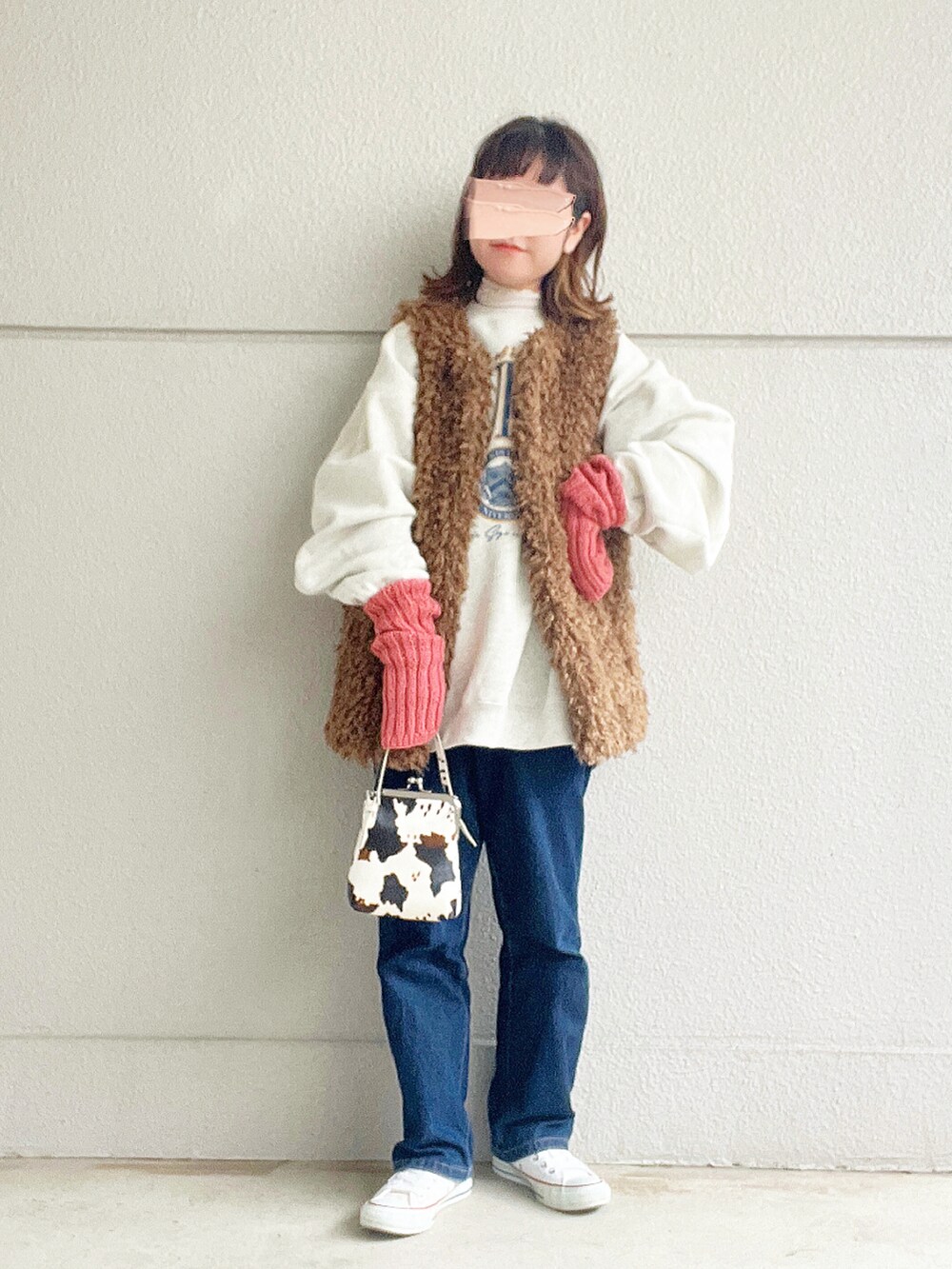 ベージュ系のスウェット、ブラウン系のベスト、ブルー系のデニムパンツを着用したレディースの冬コーディネートの2枚目の写真