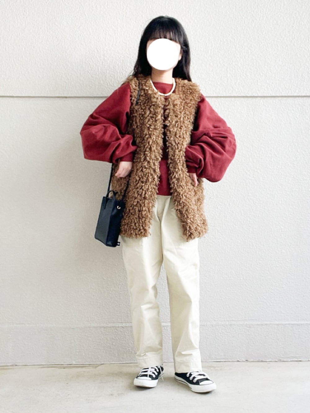 レッド系のスウェット、ブラウン系のベスト、ベージュ系のその他パンツを着用したレディースの冬コーディネートの2枚目の写真