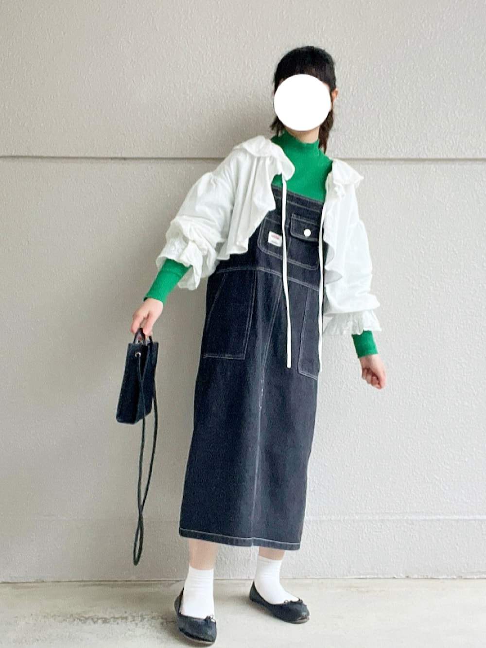 グリーン系のTシャツ/カットソー、ホワイト系のカーディガン/ボレロ、ブラック系のジャンパースカートを着用したレディースの冬コーディネートの2枚目の写真