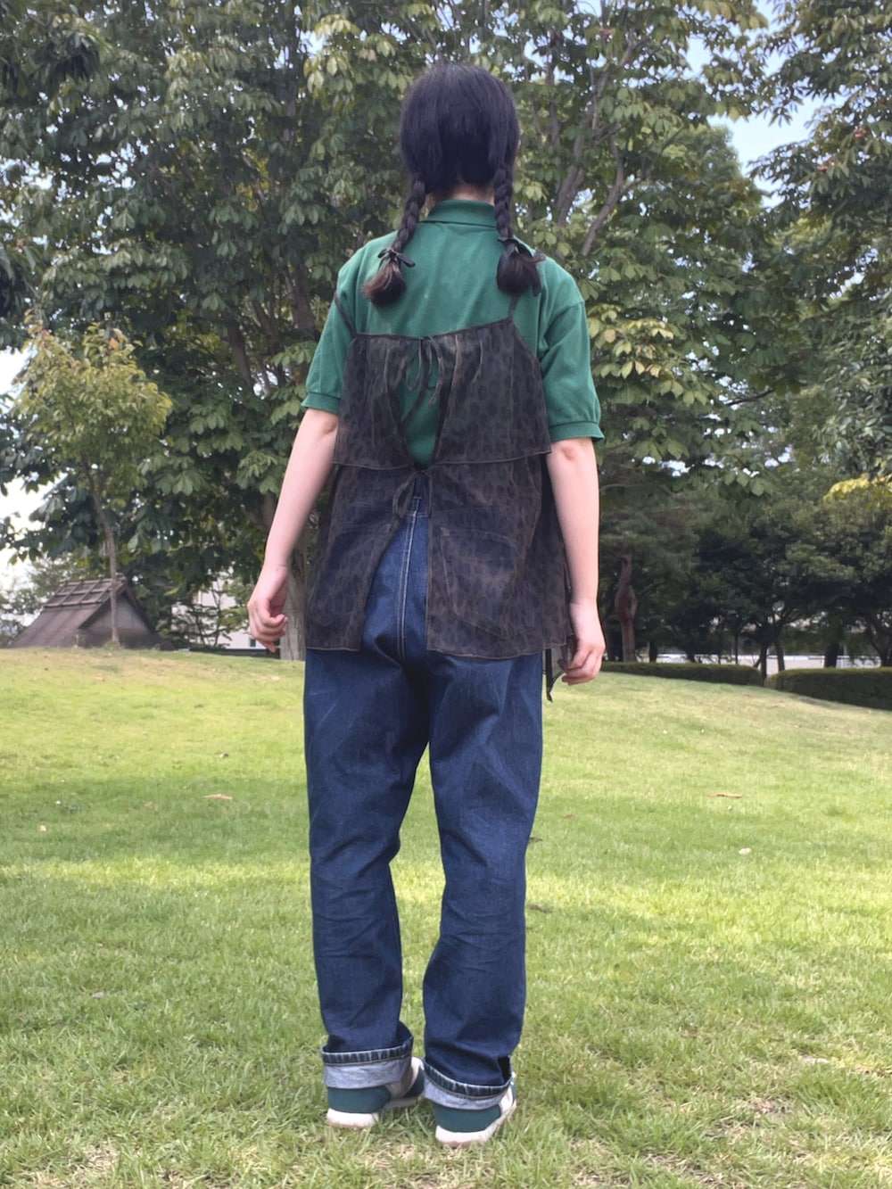 グリーン系のスニーカー、ブラウン系のキャミソール、ブルー系のデニムパンツを着用したレディースの秋コーディネートの2枚目の写真