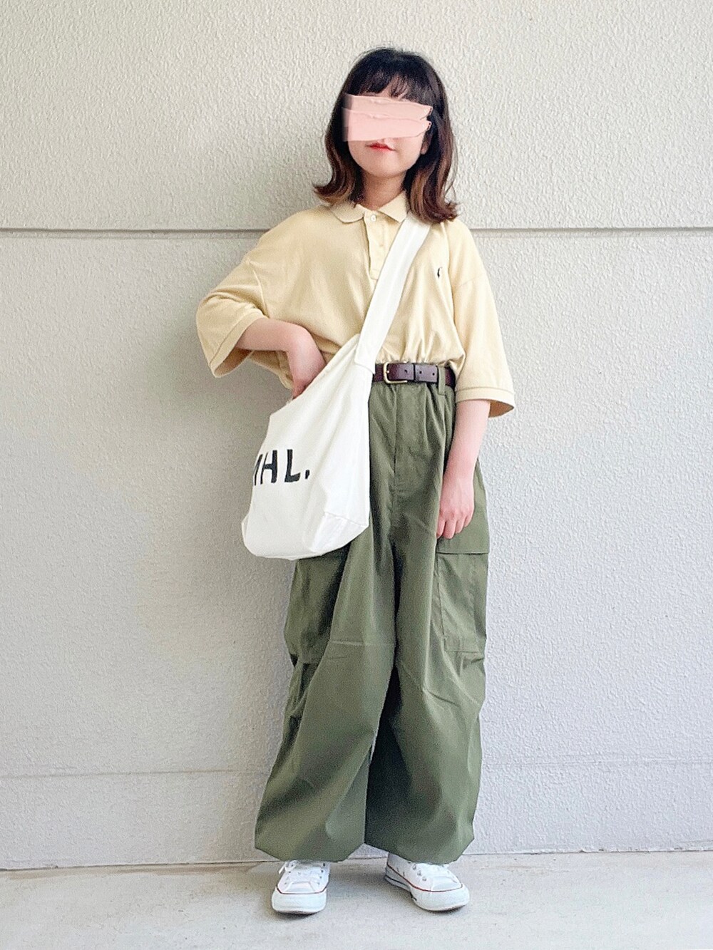 ベージュ系のポロシャツ、グリーン系のカーゴパンツ、ホワイト系のショルダーバッグを着用したレディースの春コーディネートの2枚目の写真