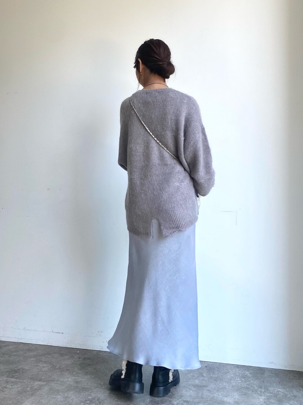 グレー系のスカート、グレー系のニット/セーター、シルバー系のショルダーバッグを着用したレディースの冬コーディネートの3枚目の写真