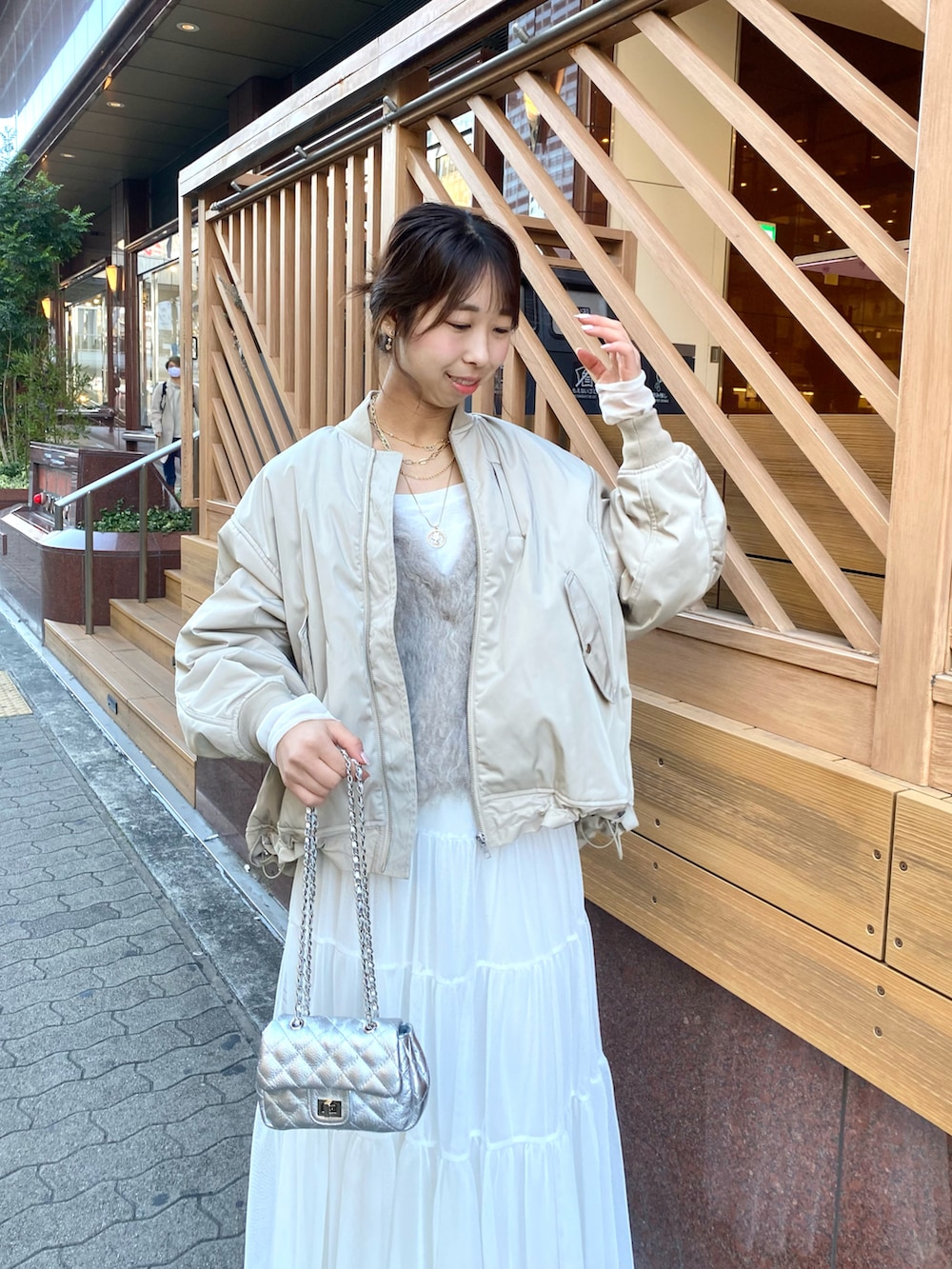 ベージュ系のベスト、ベージュ系のMA-1、ホワイト系のスカートを着用したレディースの秋コーディネートの3枚目の写真