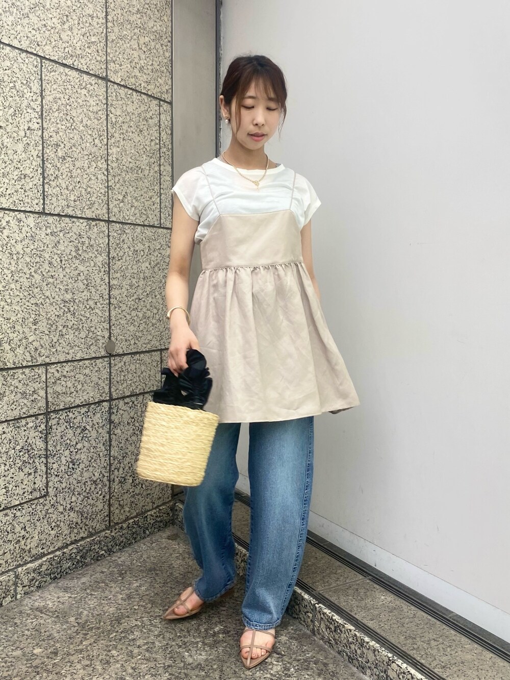 ベージュ系のキャミソール、ブルー系のデニムパンツ、ブラウン系のサンダルを着用したレディースの春コーディネートの2枚目の写真