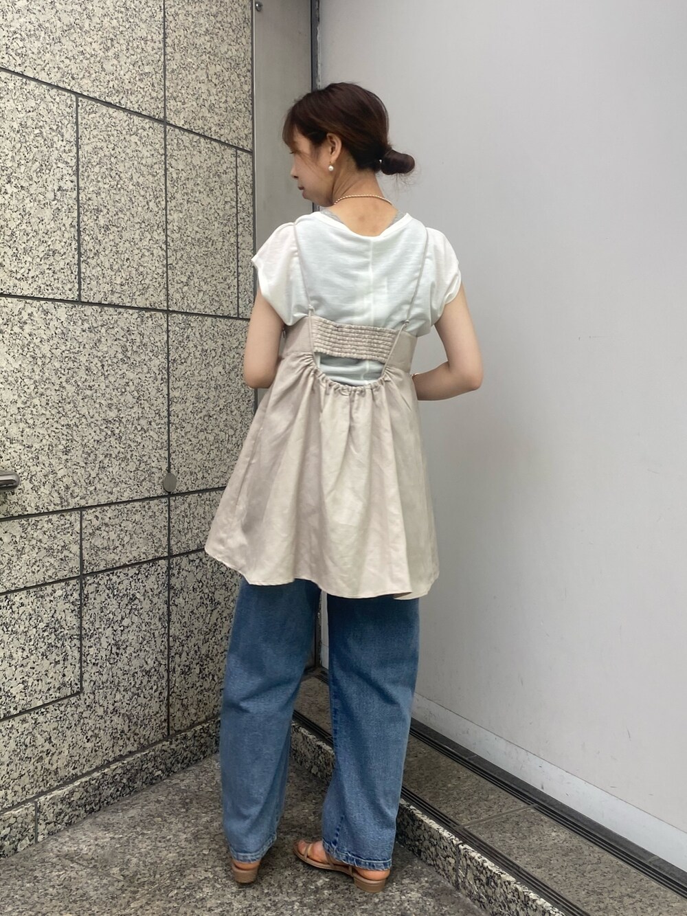 ベージュ系のキャミソール、ブルー系のデニムパンツ、ブラウン系のサンダルを着用したレディースの春コーディネートの3枚目の写真