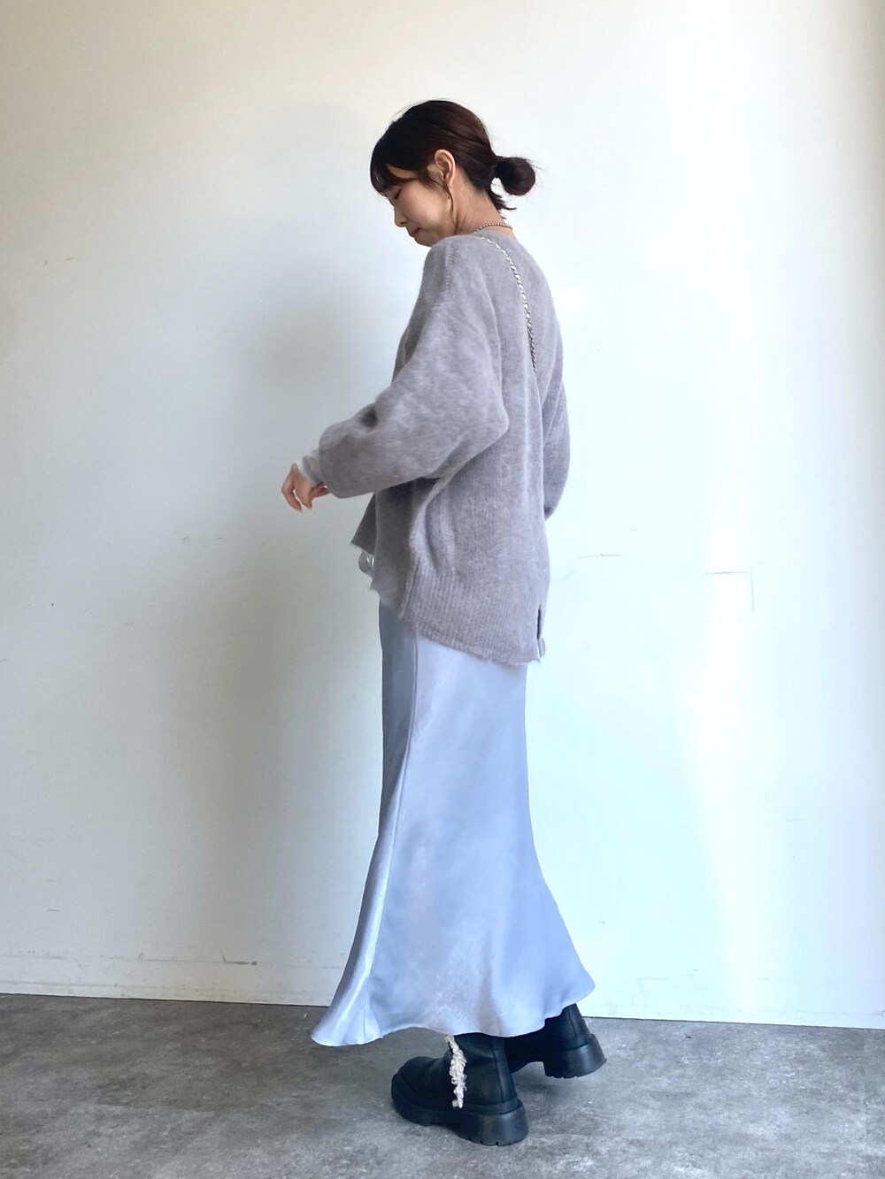 グレー系のスカート、グレー系のニット/セーター、シルバー系のショルダーバッグを着用したレディースの冬コーディネートの2枚目の写真