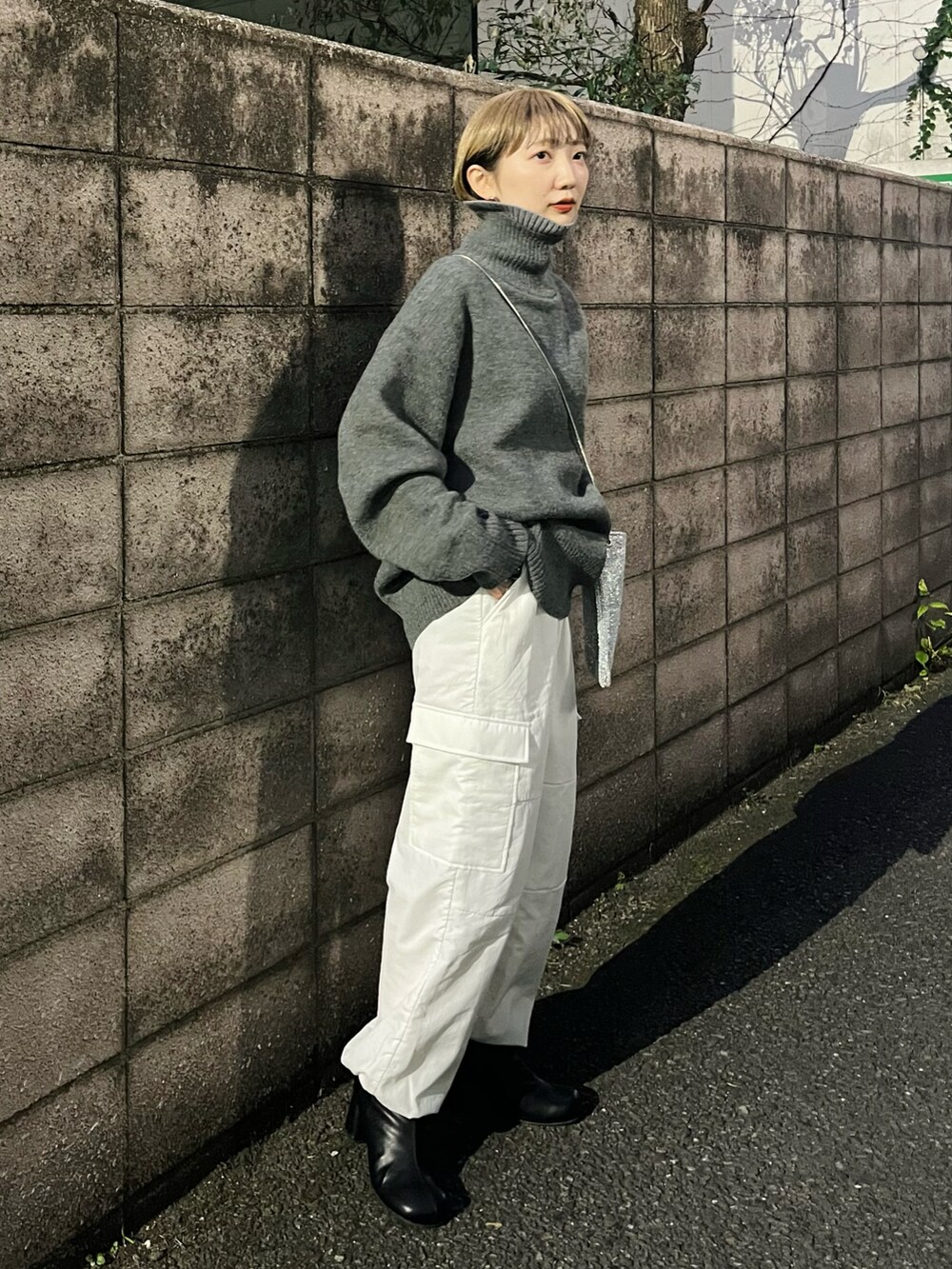ホワイト系のカーゴパンツ、ブラック系のブーツ、シルバー系のショルダーバッグを着用したレディースの冬コーディネートの4枚目の写真