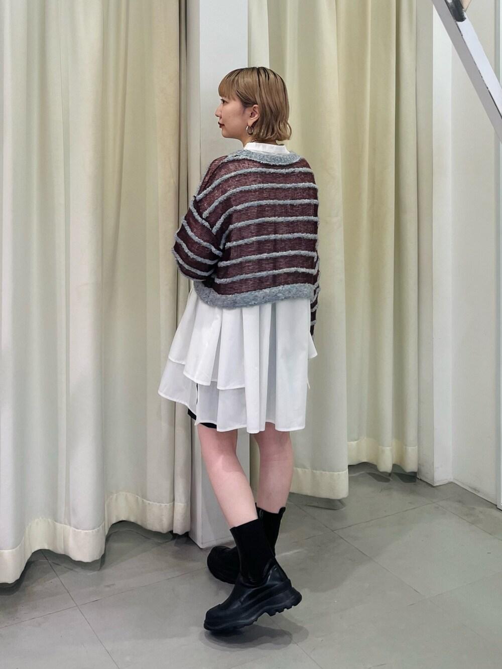 ブルー系のニット/セーター、ホワイト系のワンピース、ブラック系のブーツを着用したレディースの秋コーディネートの3枚目の写真