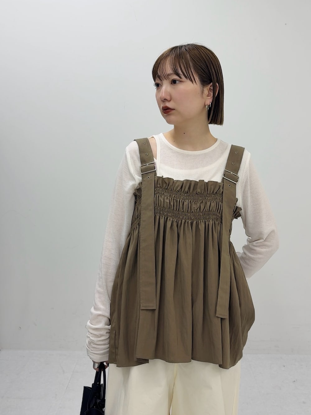 グリーン系のその他トップス、ブラック系のハンドバッグ、ホワイト系のその他パンツを着用したレディースの春コーディネートの3枚目の写真