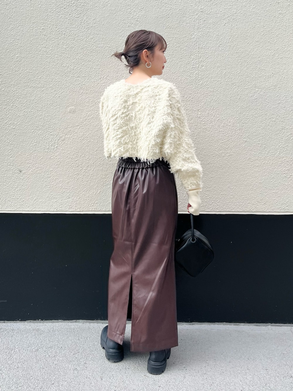 ホワイト系のカーディガン/ボレロ、ブラウン系のスカート、ブラック系のハンドバッグを着用したレディースの秋コーディネートの3枚目の写真