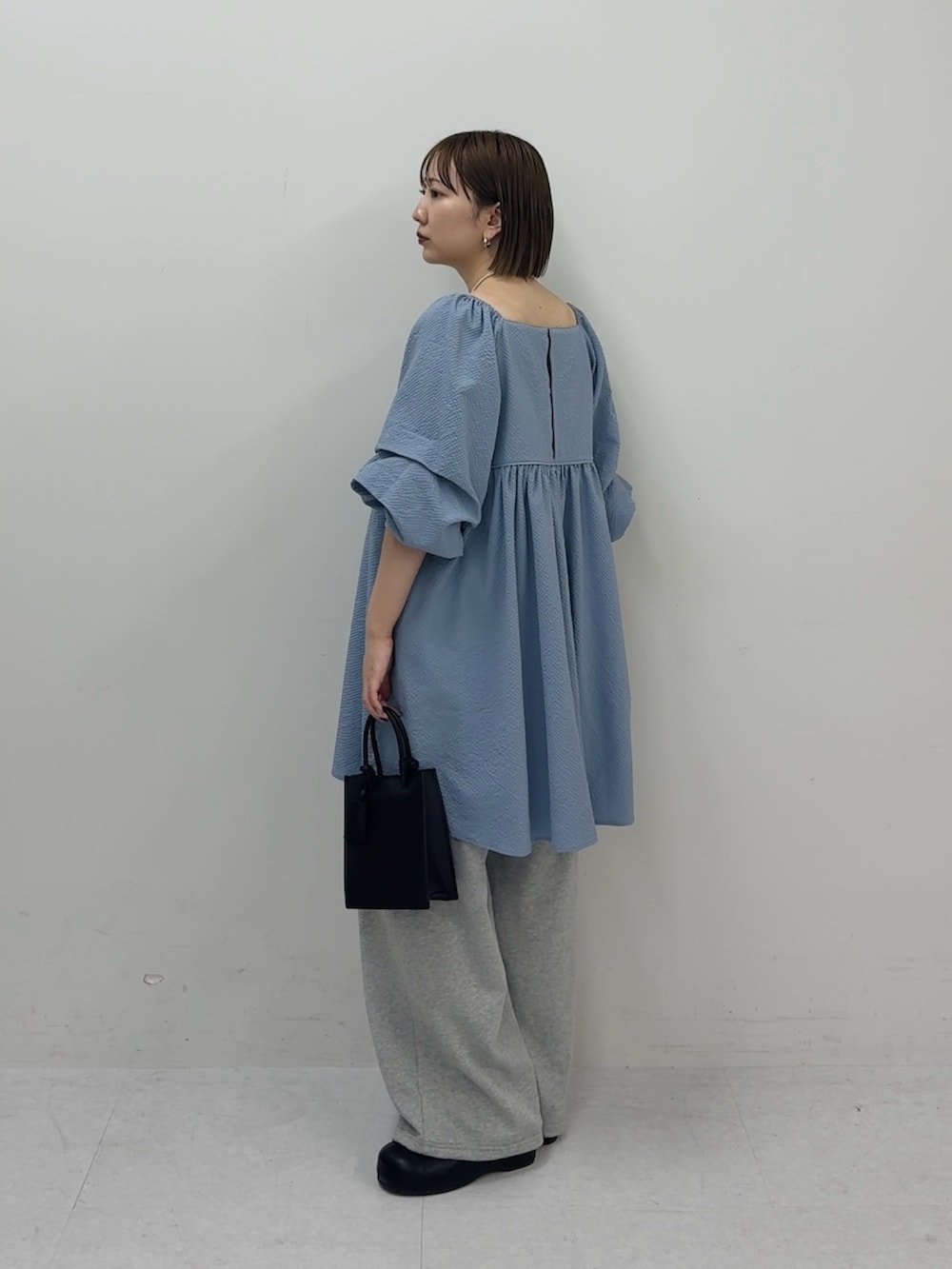 ブルー系のワンピース、グレー系のその他パンツ、ブラック系のハンドバッグを着用したレディースの春コーディネートの2枚目の写真