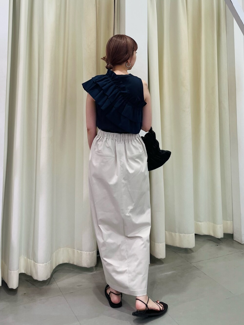 ブルー系のタンクトップ、ベージュ系のスカート、ブラック系のハンドバッグを着用したレディースの夏コーディネートの2枚目の写真