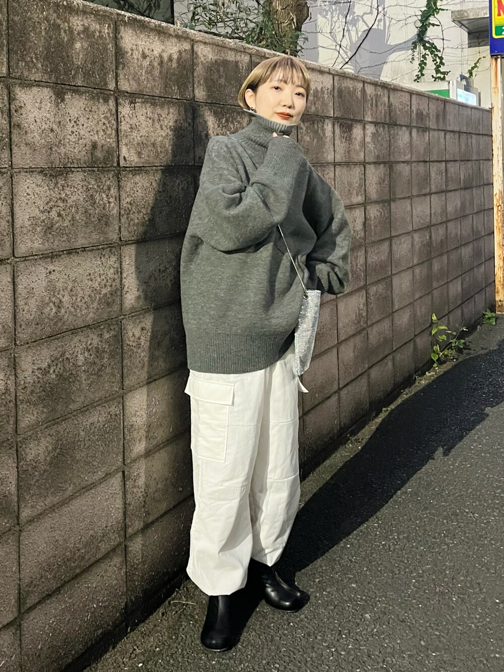 ホワイト系のカーゴパンツ、ブラック系のブーツ、シルバー系のショルダーバッグを着用したレディースの冬コーディネートの2枚目の写真