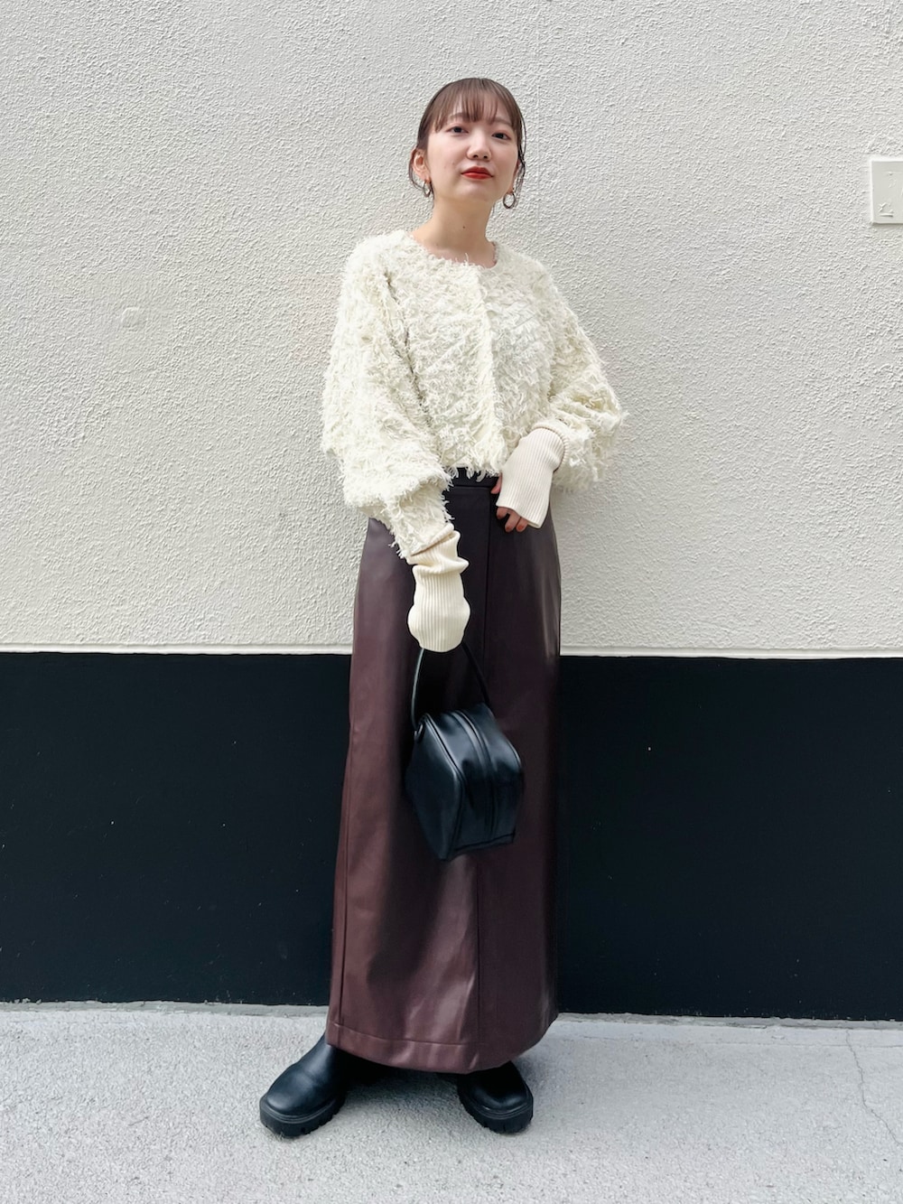 ホワイト系のカーディガン/ボレロ、ブラウン系のスカート、ブラック系のハンドバッグを着用したレディースの秋コーディネートの2枚目の写真
