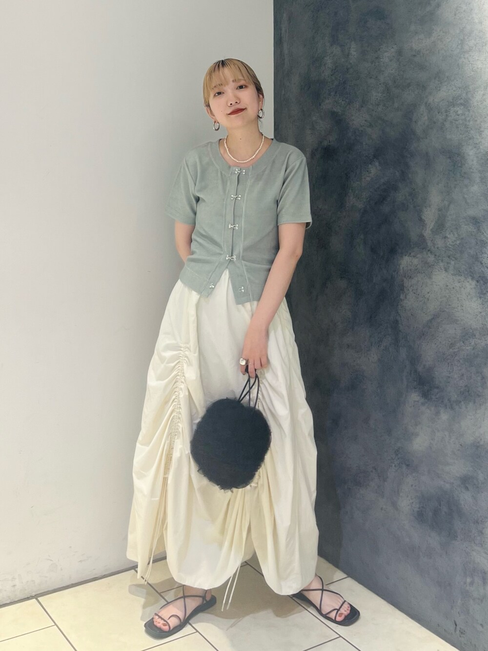 グリーン系のTシャツ/カットソー、ホワイト系のスカート、ブラック系のショルダーバッグを着用したレディースの夏コーディネートの4枚目の写真