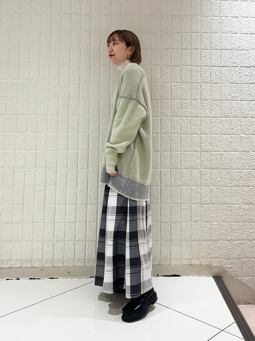 グレー系のカーディガン/ボレロ、ブラック系のスカート、ホワイト系のTシャツ/カットソーを着用したレディースの秋コーディネートの3枚目の写真