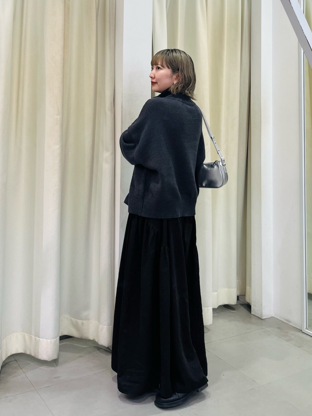 シルバー系のショルダーバッグ、ブラック系のワンピースを着用したレディースの秋コーディネートの3枚目の写真