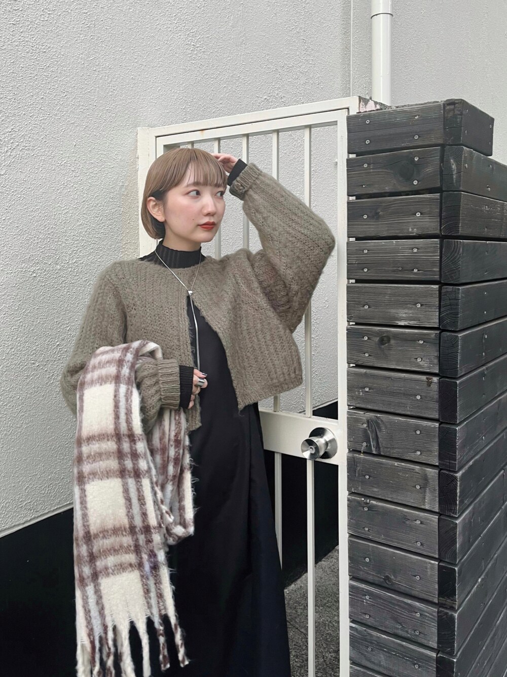 グリーン系のワンピース、ブラック系のブーツ、ホワイト系のマフラーを着用したレディースの冬コーディネートの5枚目の写真