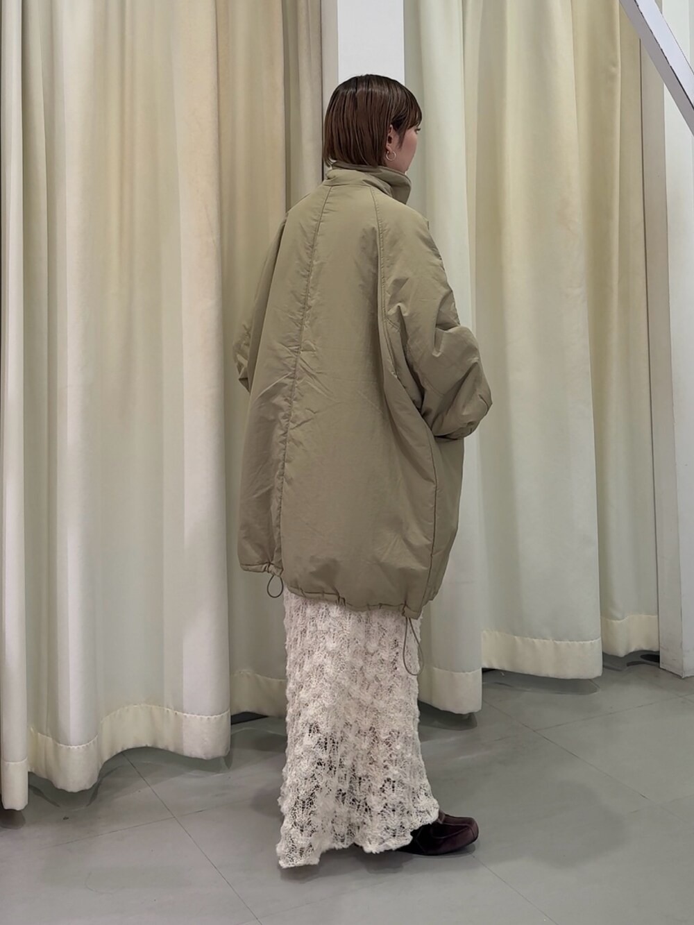 グリーン系のダウンジャケット/コート、ホワイト系のスカート、ブラウン系のスニーカーを着用したレディースの秋コーディネートの3枚目の写真