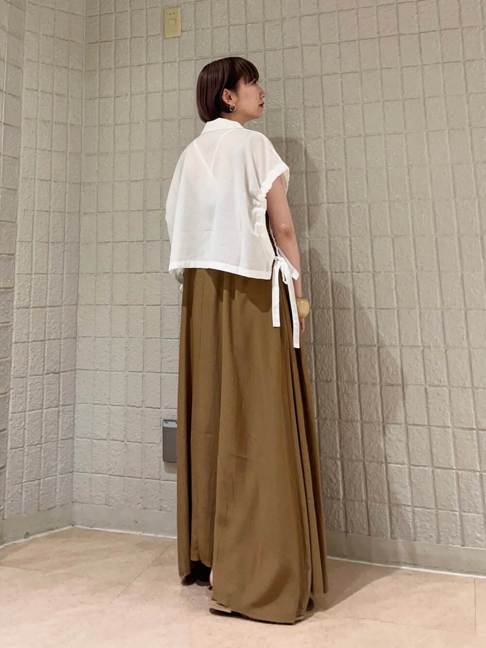 ホワイト系のシャツ/ブラウス、イエロー系のワンピース、ゴールド系のサンダルを着用したレディースの夏コーディネートの3枚目の写真