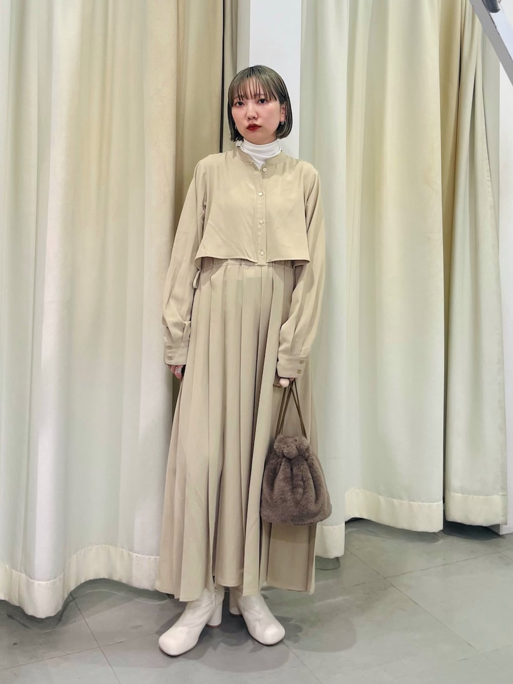 ホワイト系のブーツ、ベージュ系のワンピース、ホワイト系のTシャツ/カットソーを着用したレディースの秋コーディネートの2枚目の写真