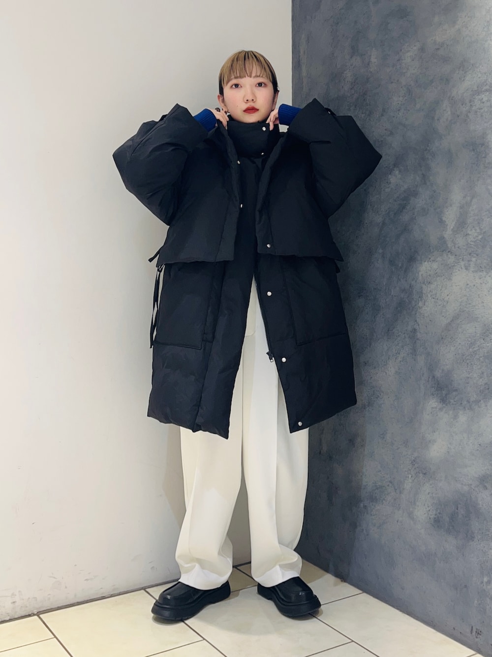 ブラック系のダウンジャケット/コート、ホワイト系のその他パンツ、ブルー系のニット/セーターを着用したレディースの冬コーディネートの2枚目の写真