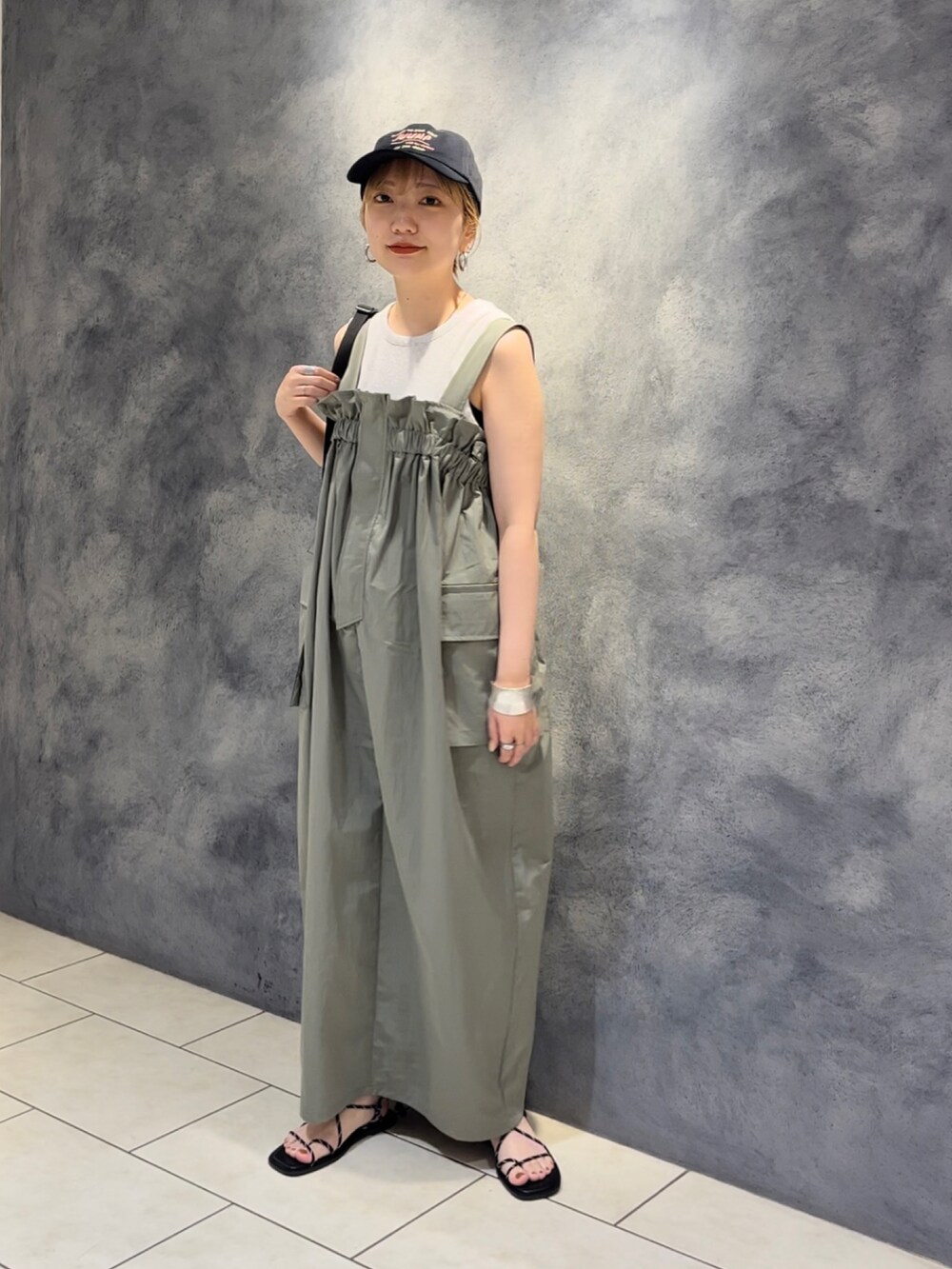 グリーン系のワンピース、ブラック系のショルダーバッグ、ベージュ系のタンクトップを着用したレディースの夏コーディネートの2枚目の写真