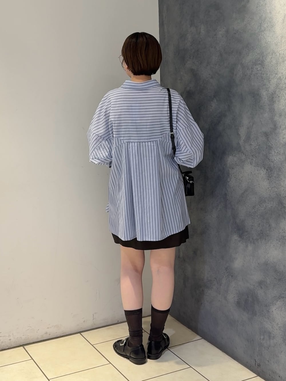 ブルー系のチュニック、ブラウン系のスカート、ブラック系のショルダーバッグを着用したレディースの夏コーディネートの3枚目の写真