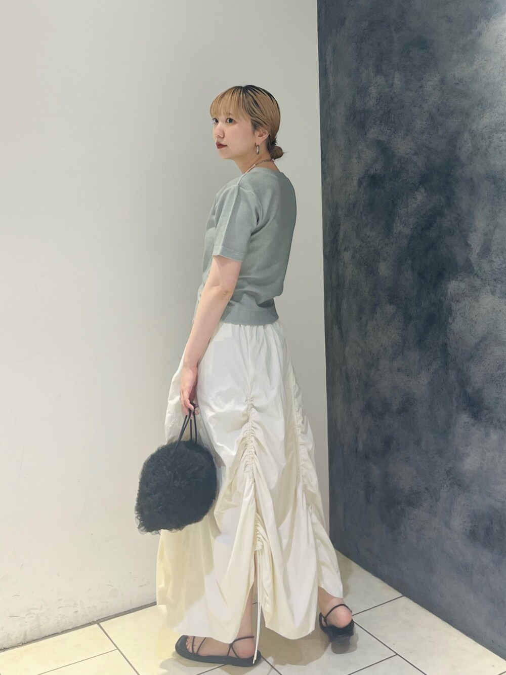 グリーン系のTシャツ/カットソー、ホワイト系のスカート、ブラック系のショルダーバッグを着用したレディースの夏コーディネートの3枚目の写真