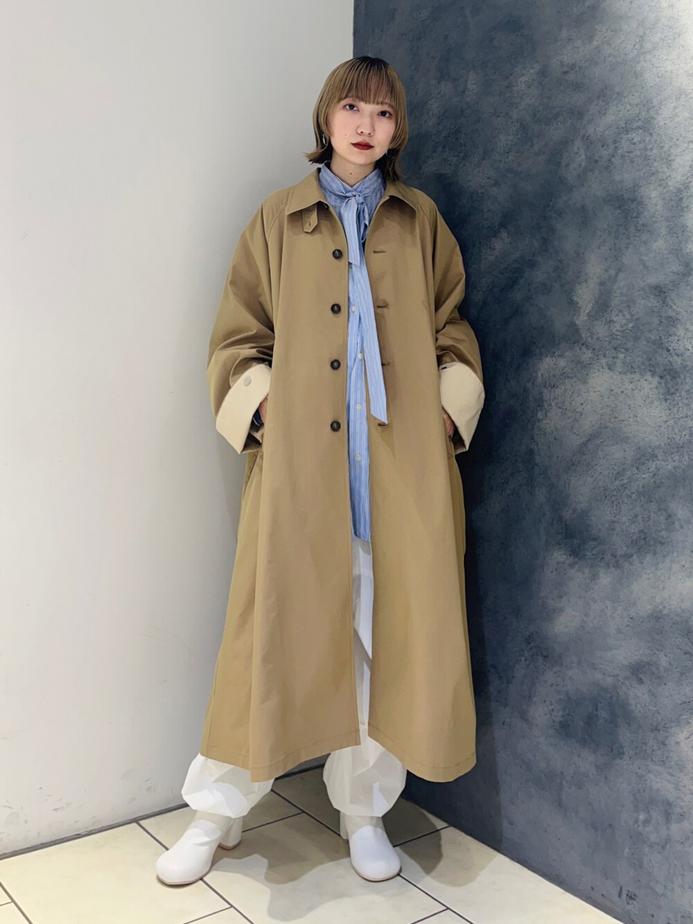 ブルー系のシャツ/ブラウス、ベージュ系のステンカラーコート、ホワイト系のその他パンツを着用したレディースの冬コーディネートの2枚目の写真