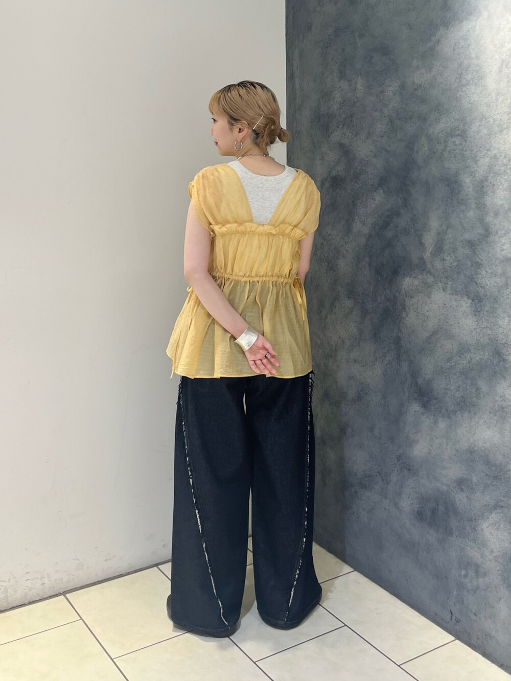 オレンジ系のシャツ/ブラウス、ブルー系のデニムパンツ、ホワイト系のハンドバッグを着用したレディースの夏コーディネートの4枚目の写真