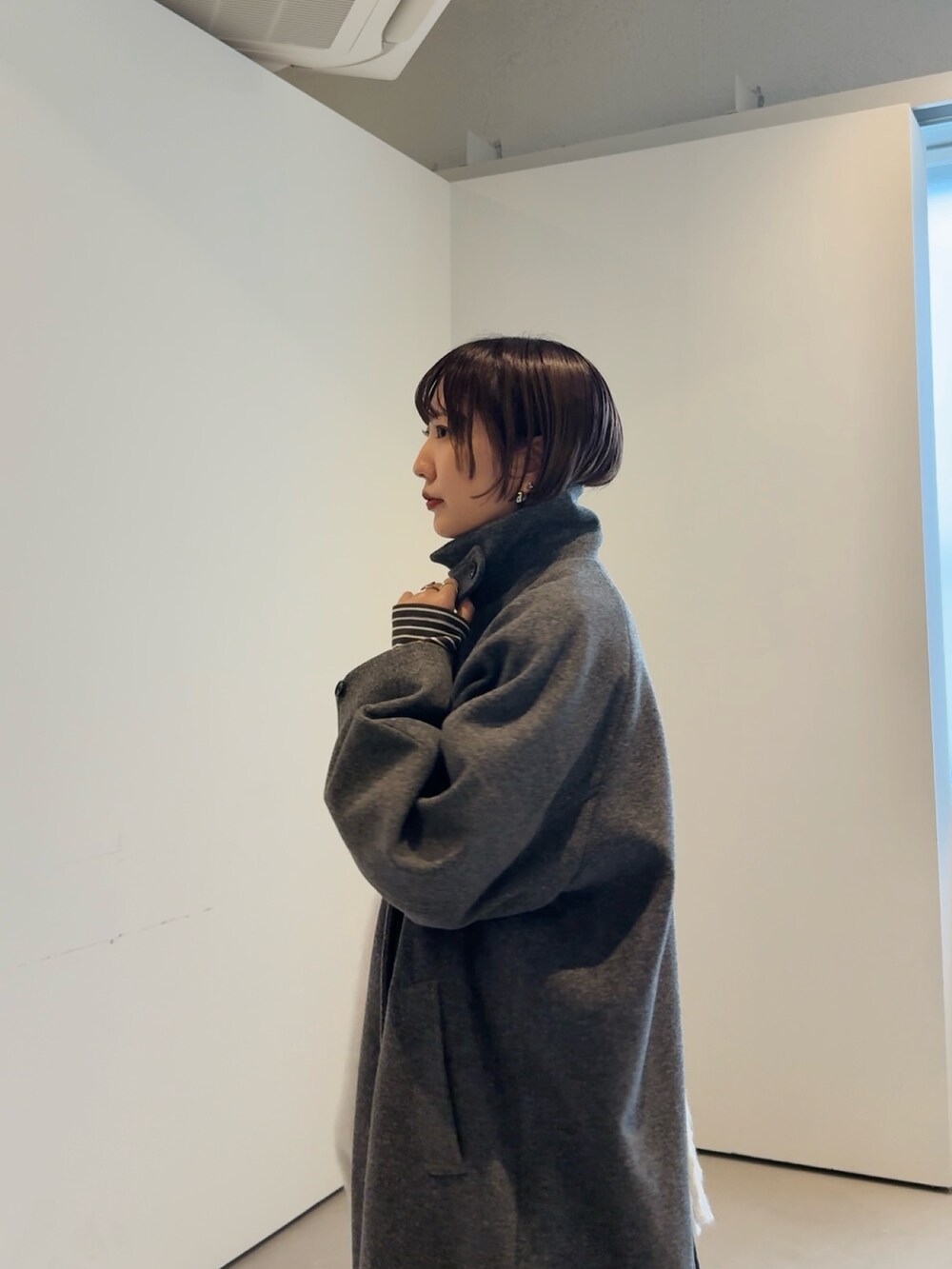 グレー系のステンカラーコート、ブラック系のマフラーを着用したレディースの秋コーディネートの3枚目の写真