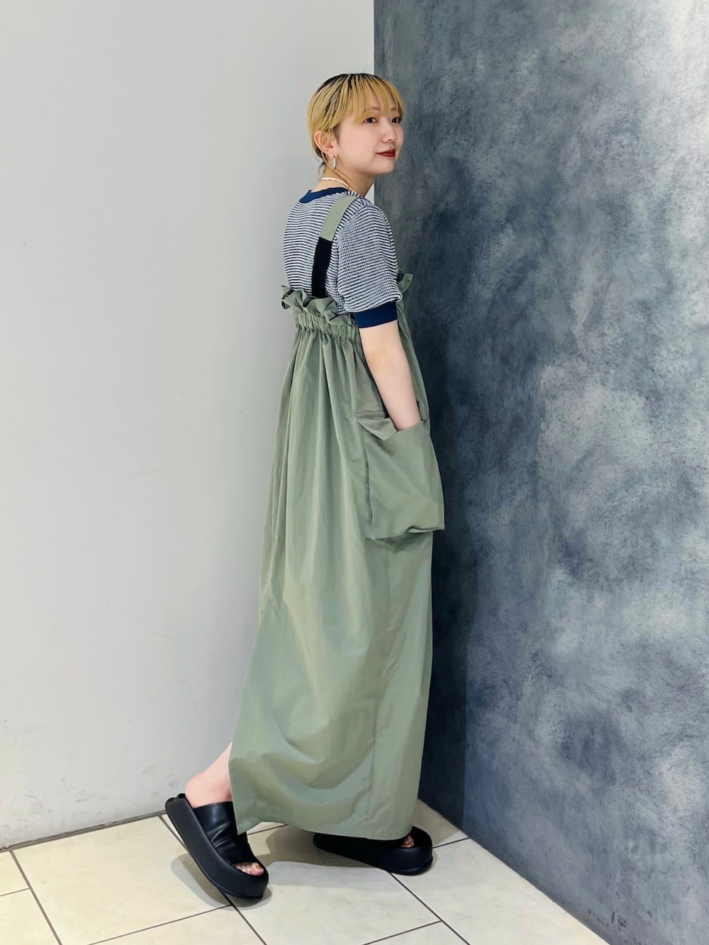 グリーン系のワンピース、ブルー系のニット/セーター、ブラック系のサンダルを着用したレディースの春コーディネートの2枚目の写真