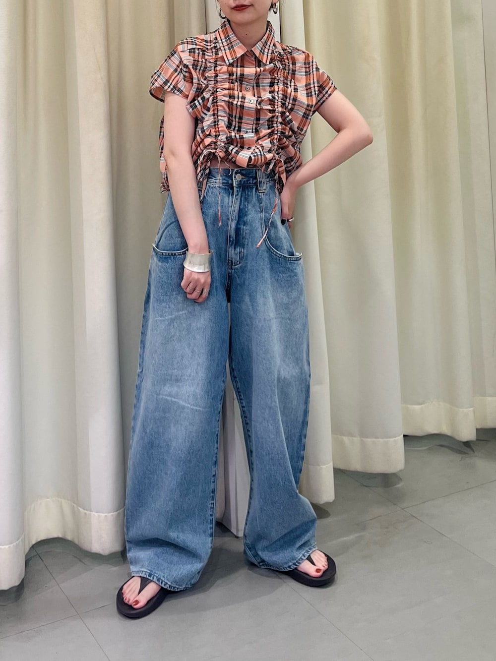 オレンジ系のシャツ/ブラウス、ブルー系のデニムパンツを着用したレディースの夏コーディネートの2枚目の写真