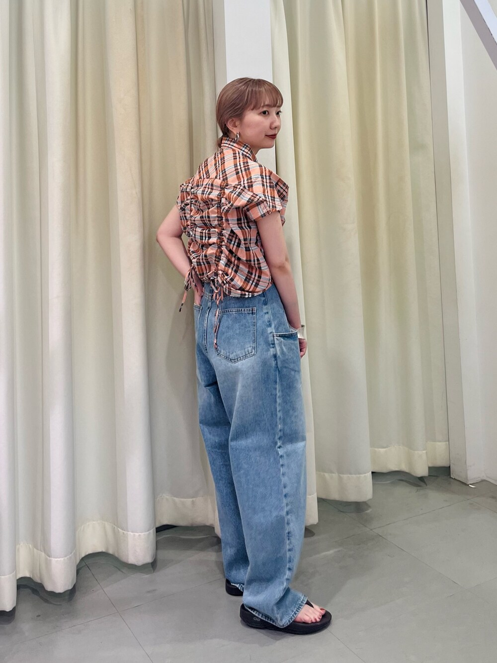 オレンジ系のシャツ/ブラウス、ブルー系のデニムパンツを着用したレディースの夏コーディネートの3枚目の写真