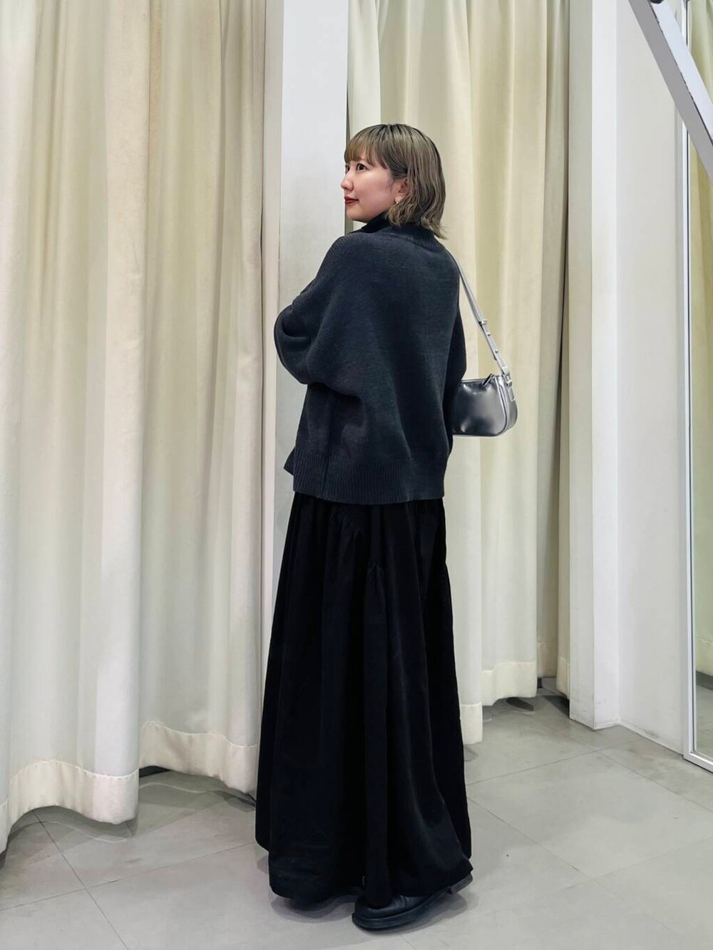 ブラック系のワンピース、シルバー系のショルダーバッグを着用したレディースの秋コーディネートの4枚目の写真