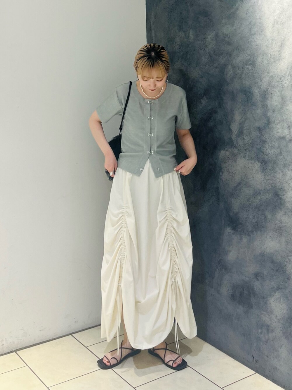 グリーン系のTシャツ/カットソー、ホワイト系のスカート、ブラック系のショルダーバッグを着用したレディースの夏コーディネートの2枚目の写真