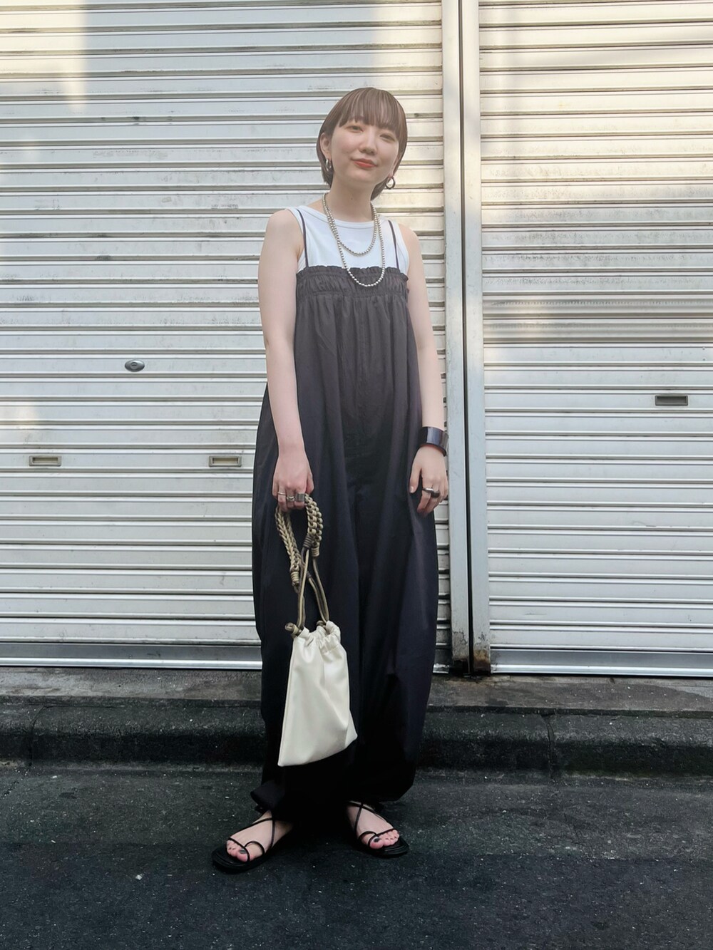 グレー系のサロペット/オーバーオール、ホワイト系のタンクトップ、ブラック系のサンダルを着用したレディースの夏コーディネートの2枚目の写真
