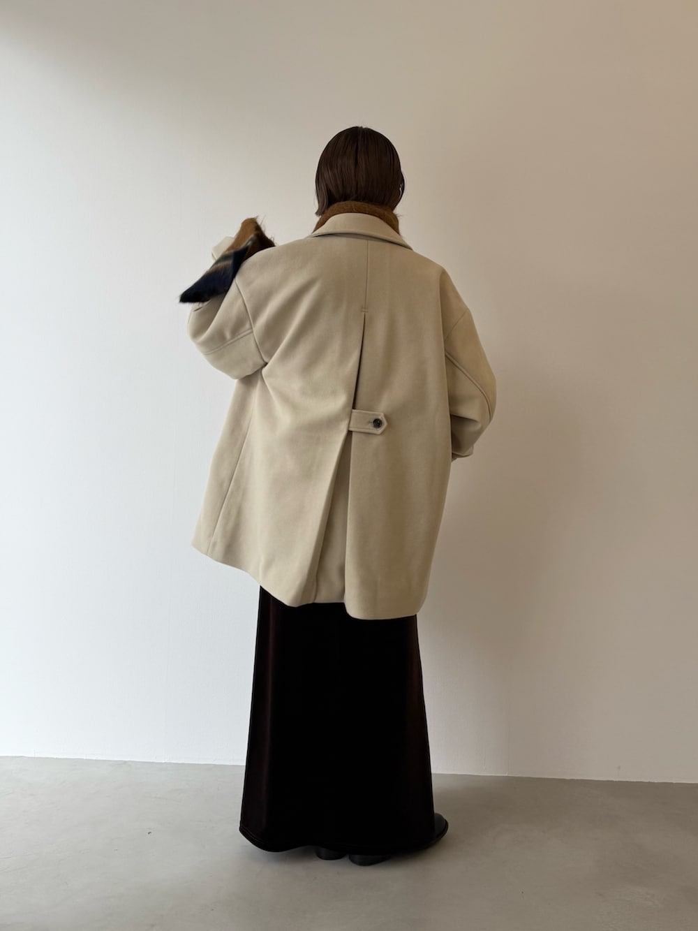 ブラック系のスカート、ベージュ系のその他アウター、イエロー系のマフラーを着用したレディースの秋コーディネートの3枚目の写真