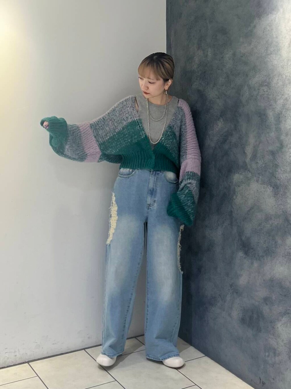 ブルー系のデニムパンツ、ホワイト系のブーツ、グレー系のタンクトップを着用したレディースの秋コーディネートの3枚目の写真