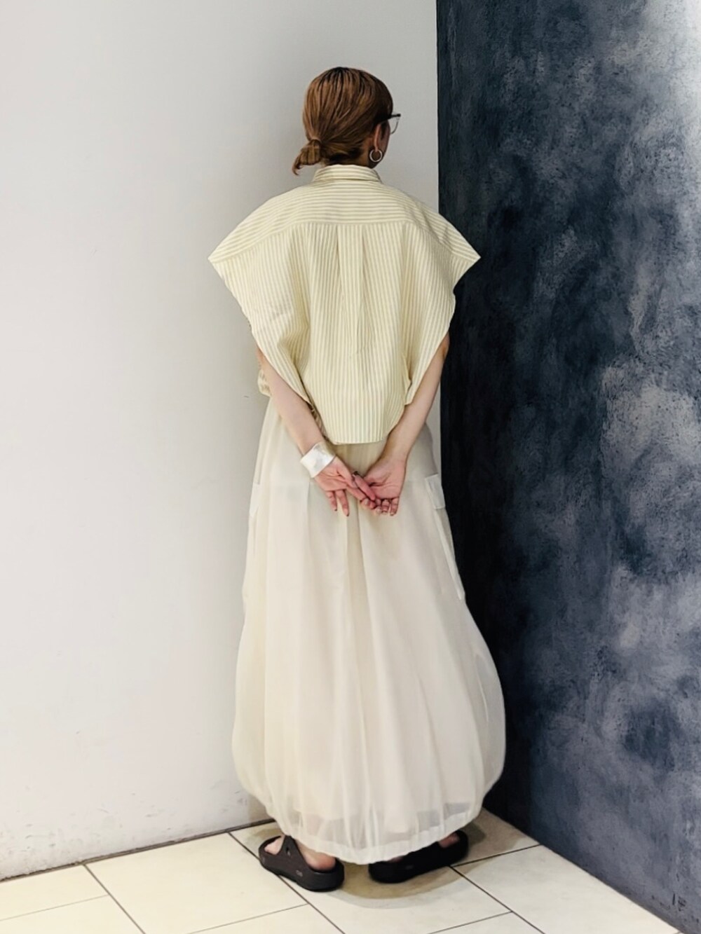 イエロー系のシャツ/ブラウス、ホワイト系のスカート、ブラウン系のサンダルを着用したレディースの春コーディネートの4枚目の写真