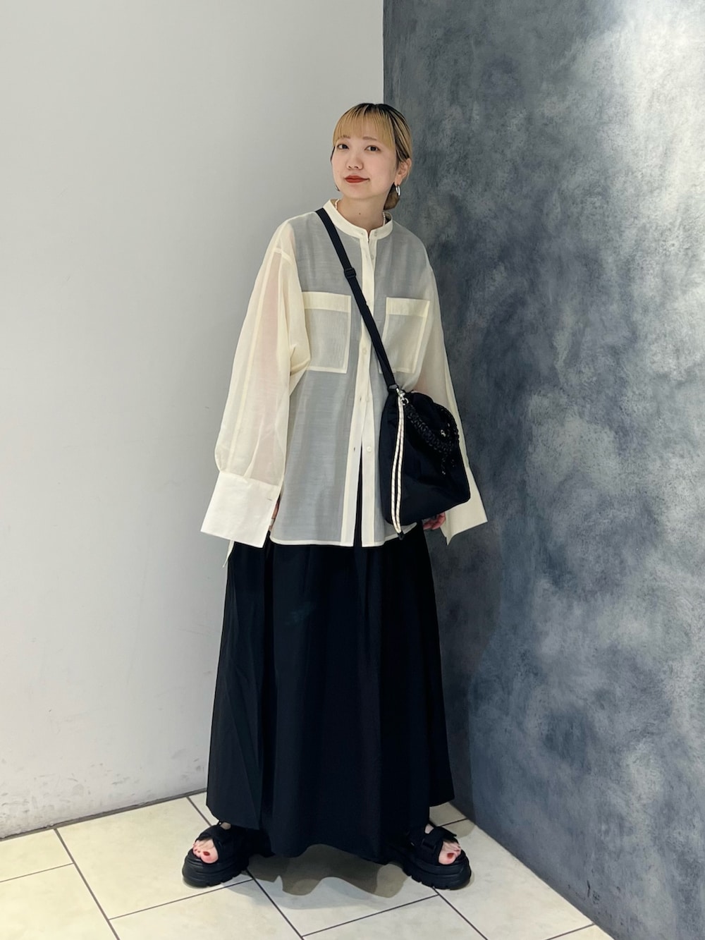 ブラック系のワンピース、ホワイト系のシャツ/ブラウス、ブラック系のサンダルを着用したレディースの夏コーディネートの2枚目の写真