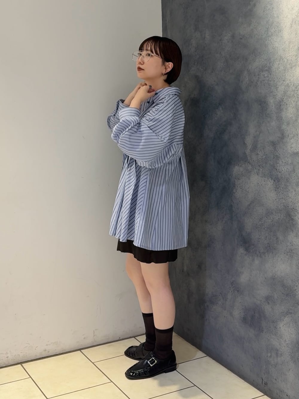 ブルー系のチュニック、ブラウン系のスカート、ブラック系のショルダーバッグを着用したレディースの夏コーディネートの2枚目の写真