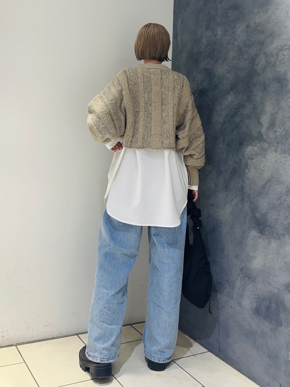 ベージュ系のニット/セーター、ホワイト系のシャツ/ブラウス、ブルー系のデニムパンツを着用したレディースの冬コーディネートの4枚目の写真