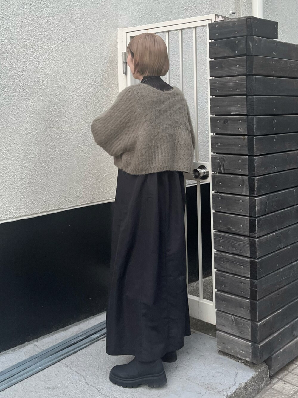 グリーン系のワンピース、ブラック系のブーツ、ホワイト系のマフラーを着用したレディースの冬コーディネートの4枚目の写真